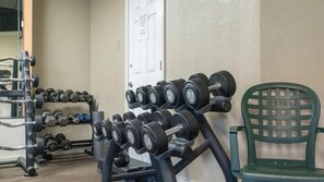 A gym with various weightlifting equipment, including dumbbells and a bench press.