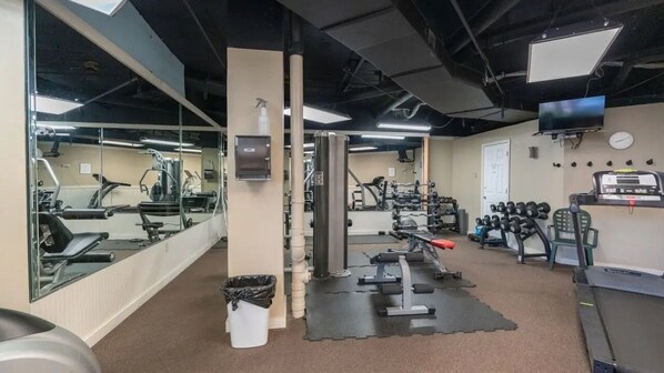A gym with exercise equipment, mirrors, and a television.
