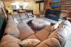 A living room with a sectional sofa, a round coffee table, and a fireplace.