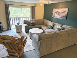 A living room with a sectional sofa, a round coffee table, and a wooden rocking chair.