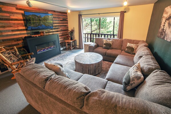 A cozy living room with a fireplace, a large sectional sofa, and a round coffee table.