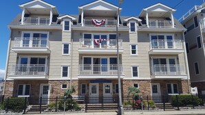 Un edificio de varios pisos con balcones, fachada de piedra y un letrero que dice 'Pleasant View by the Sea Condominiums'.