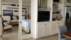 A room with a bed, a TV, a dining table, and a kitchen area.