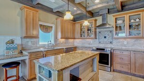 Una cocina amplia con encimeras de granito, armarios de madera y una isla grande.