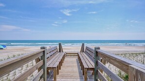 Un paseo marítimo de madera que lleva a una playa, con una vista despejada del océano.