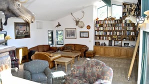 Una sala de estar acogedora con una amplia estantería, un trofeo de cabeza de alce montado y una decoración de estilo rústico.