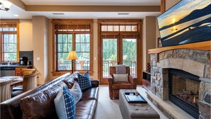 A cozy living room with a fireplace, a sofa, a chair, and a television.