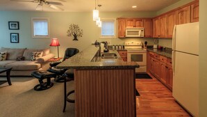 A modern kitchen with wooden cabinets, a central island, a microwave, and a refrigerator.