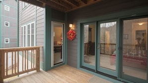 A wooden deck with a glass door leading to an interior room.