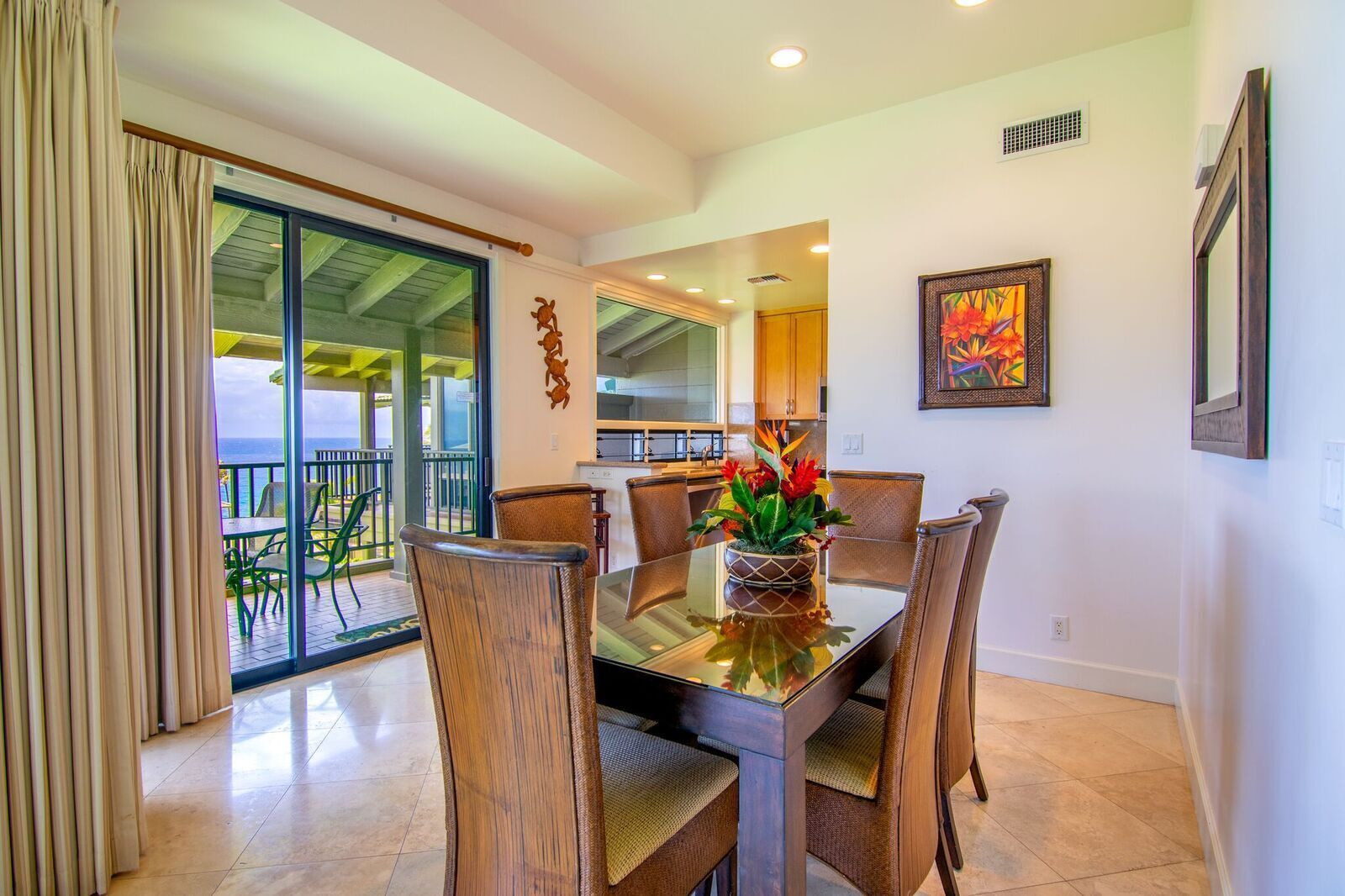 A dining area with a glass table, wicker chairs, and a potted plant.
