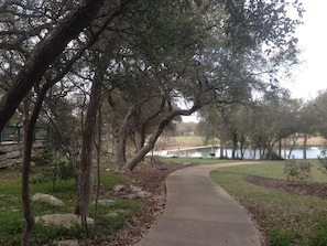 A park pathway with trees and a lake in the background.