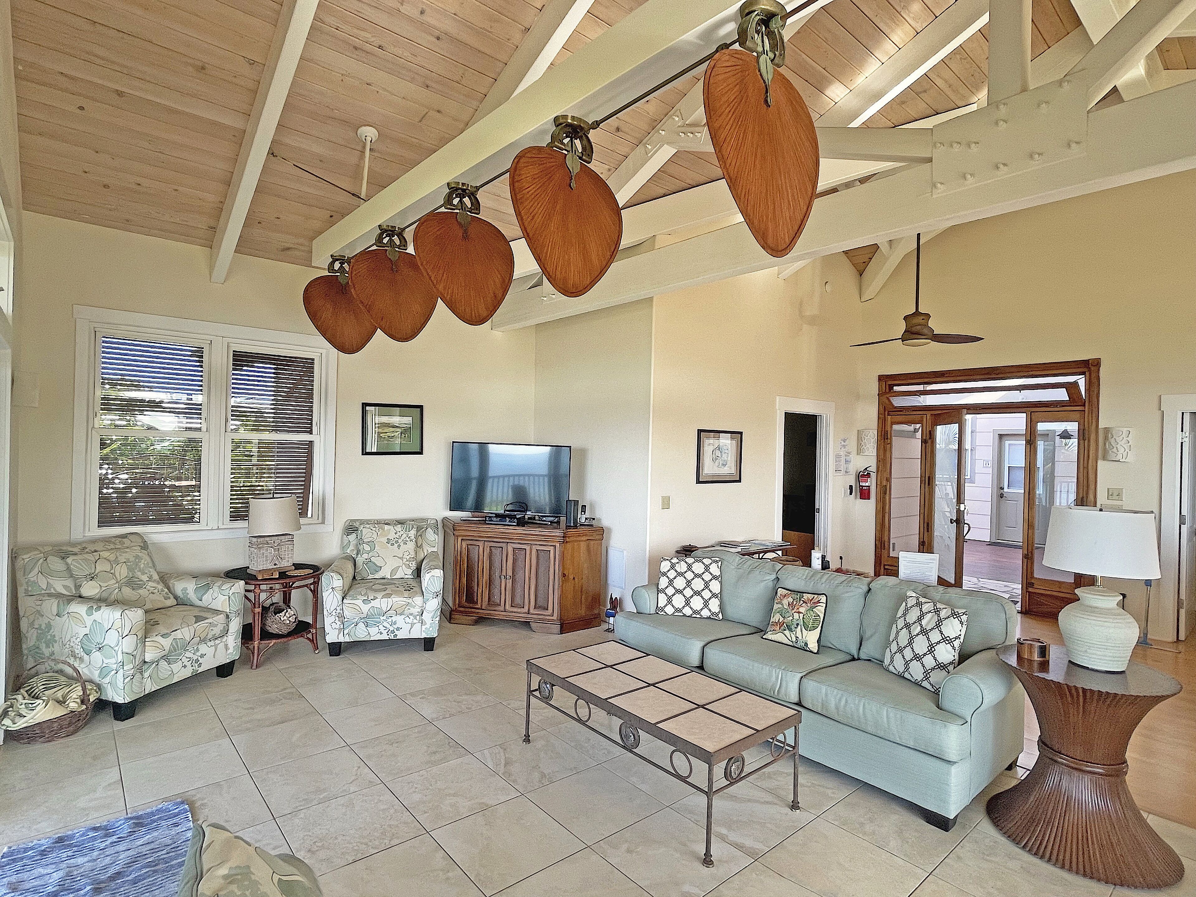 A spacious living room with a sofa, armchairs, a coffee table, and a television.