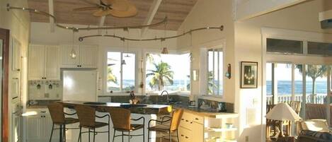 A spacious kitchen with a large island, bar stools, and a view of the ocean.