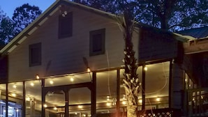 A building with a fire pit in front, surrounded by outdoor seating and a covered area with lights. - River Front, Fishing, Kayaking, Boating, Tubing on the Edisto River   (Ridgeville)
