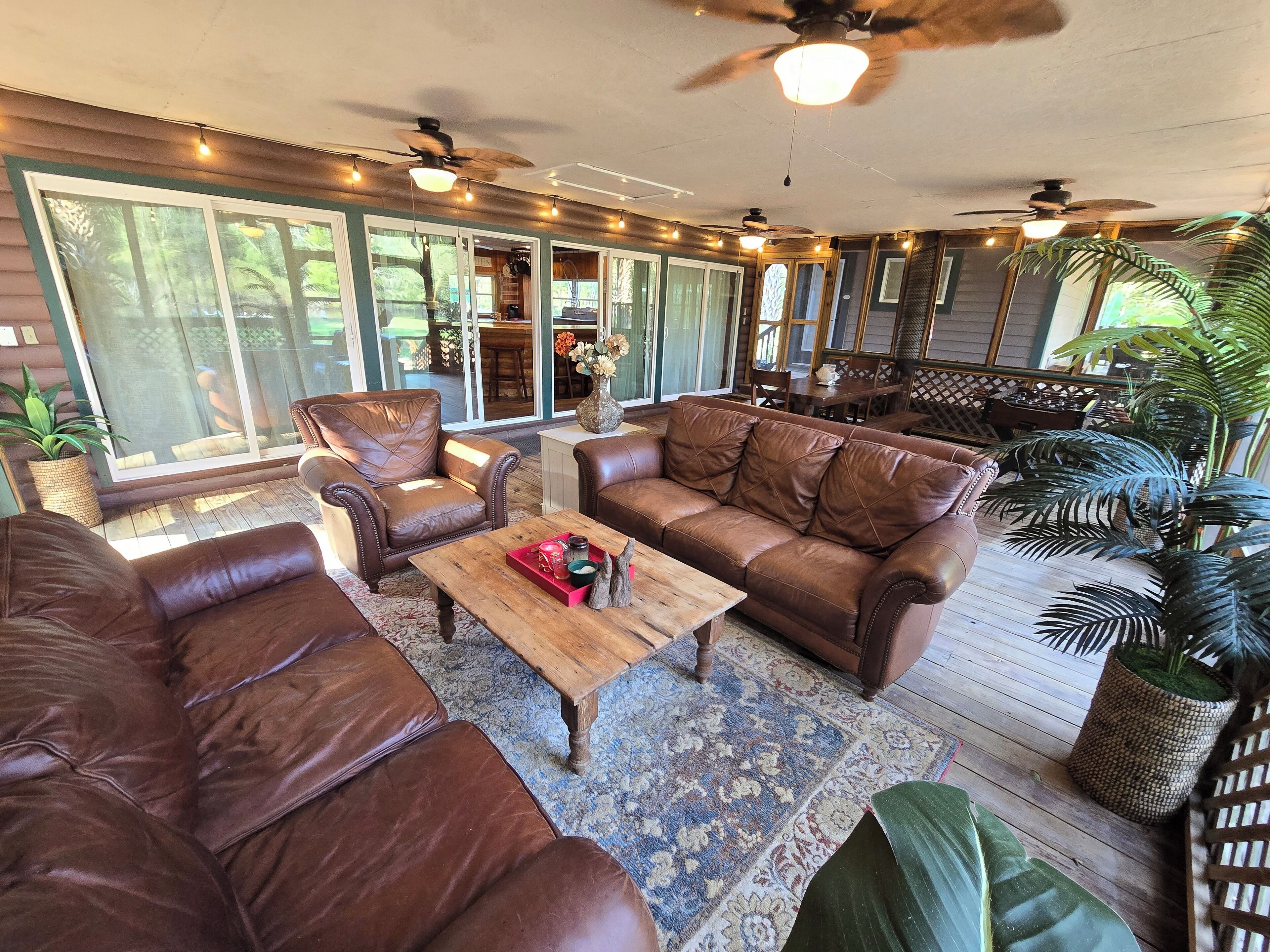 A spacious living area with leather sofas, a wooden coffee table, and a large window providing a view of the outdoors.