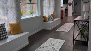 Una sala de estar moderna con asientos integrados, ventanas amplias y un pasillo que conduce a una zona de cocina.