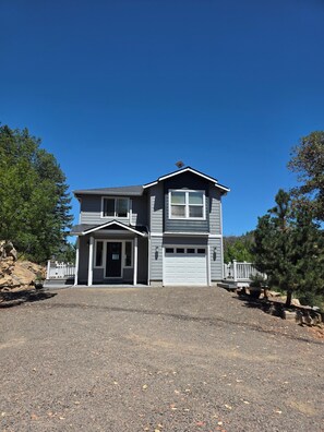 A two-story house with a garage, a covered porch, and a fenced driveway.