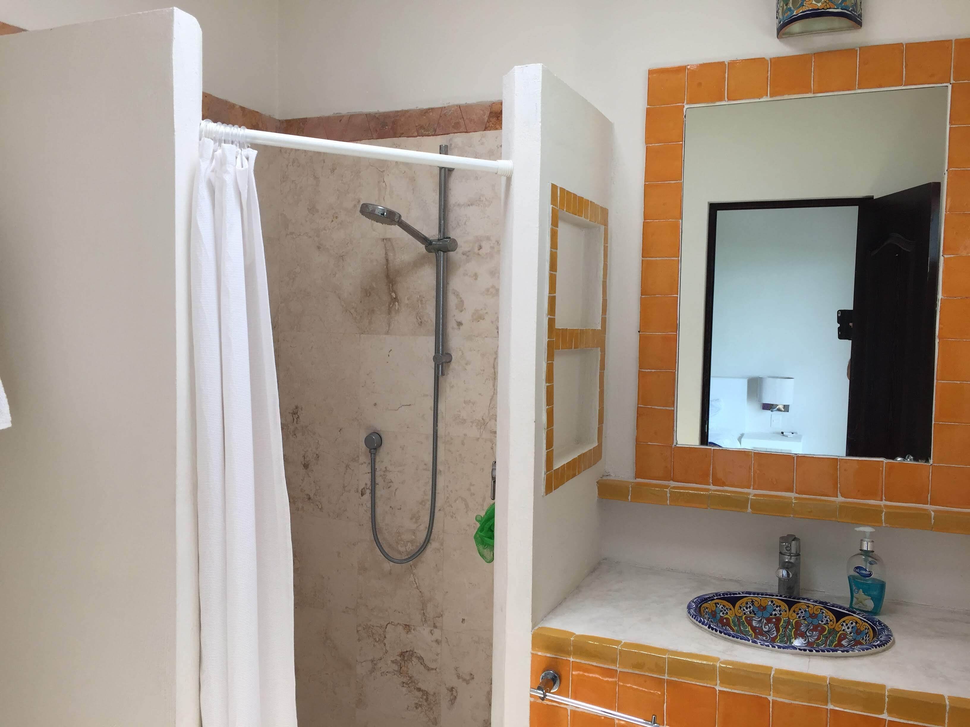 Ein Badezimmer mit Dusche, Waschbecken und Spiegel.