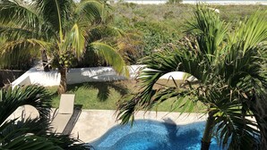 Ein Swimmingpool, umgeben von Palmen, mit Blick auf den Strand.