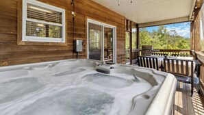 Un bain à remous sur une terrasse en bois, avec vue sur les arbres.