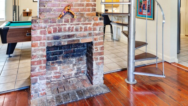 A spiral staircase with a brick fireplace, wooden flooring, and a pool table in a room with a door and a framed picture on the wall. - The Tchoup House, Rock out Nextdoor to Tipitina’s music club Uptown (new orleans)