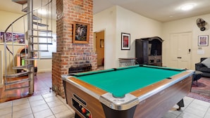 A pool table in a room with a brick fireplace, a spiral staircase, and a television. - The Tchoup House, Rock out Nextdoor to Tipitina’s music club Uptown (new orleans)