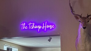 A kitchen with wooden cabinets, a neon sign reading 'The Tchoup House,' and a mounted deer head on the wall. - The Tchoup House, Rock out Nextdoor to Tipitina’s music club Uptown (new orleans)