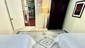 A hotel room with two beds, a door leading to a hallway, a framed picture on the wall, and a patterned rug on the floor. - The Tchoup House, Rock out Nextdoor to Tipitina’s music club Uptown (new orleans)