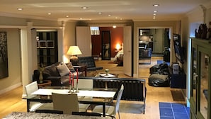 A spacious living area with a dining table, sofas, and a kitchen in the background.