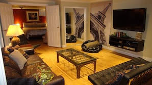 A living room with a sofa, a coffee table, a television, and a bookshelf.