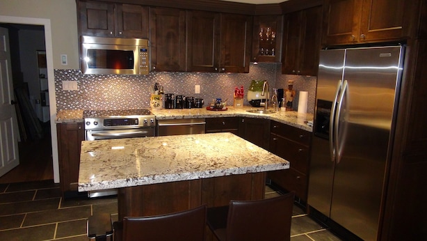 A modern kitchen with granite countertops, stainless steel appliances, and dark wood cabinetry.