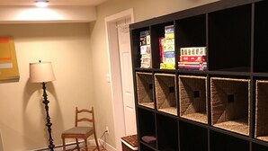 A room with a wooden floor, a chair, a lamp, and a bookshelf with storage baskets.