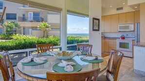 A dining area with a glass table, chairs, and a view of the ocean. - Kapalua Bay Villa 35G4 | Sunset Views | Walk to Beach (Lahaina)