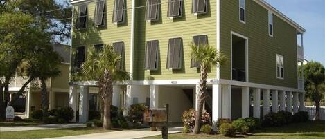 A two-story building with a green facade, multiple windows, and a front porch.