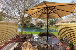 Relax in a serene outdoor space with a patio, featuring a table, chairs, and a shaded area.