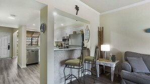 Eine moderne Küche mit weißen Schränken, einem Edelstahlkühlschrank und einer Bar mit zwei Barhocker.
