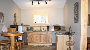 Eine kompakte Küche mit Holzschränken, einer Mikrowelle, einem Spülbecken und einem Essbereich mit Tisch und Stühlen.