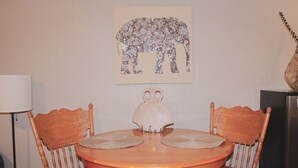 Ein Esstisch mit zwei Stühlen, einer Vase und einem gerahmten Elefantenbild an der Wand.
