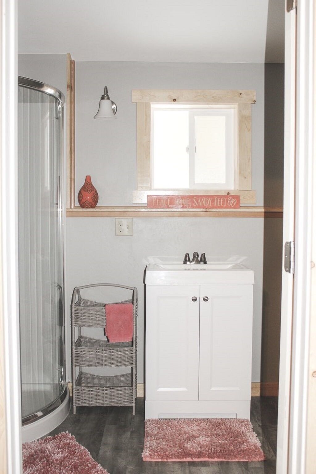 Un baño con ducha, lavabo, ventana y una cesta de mimbre.