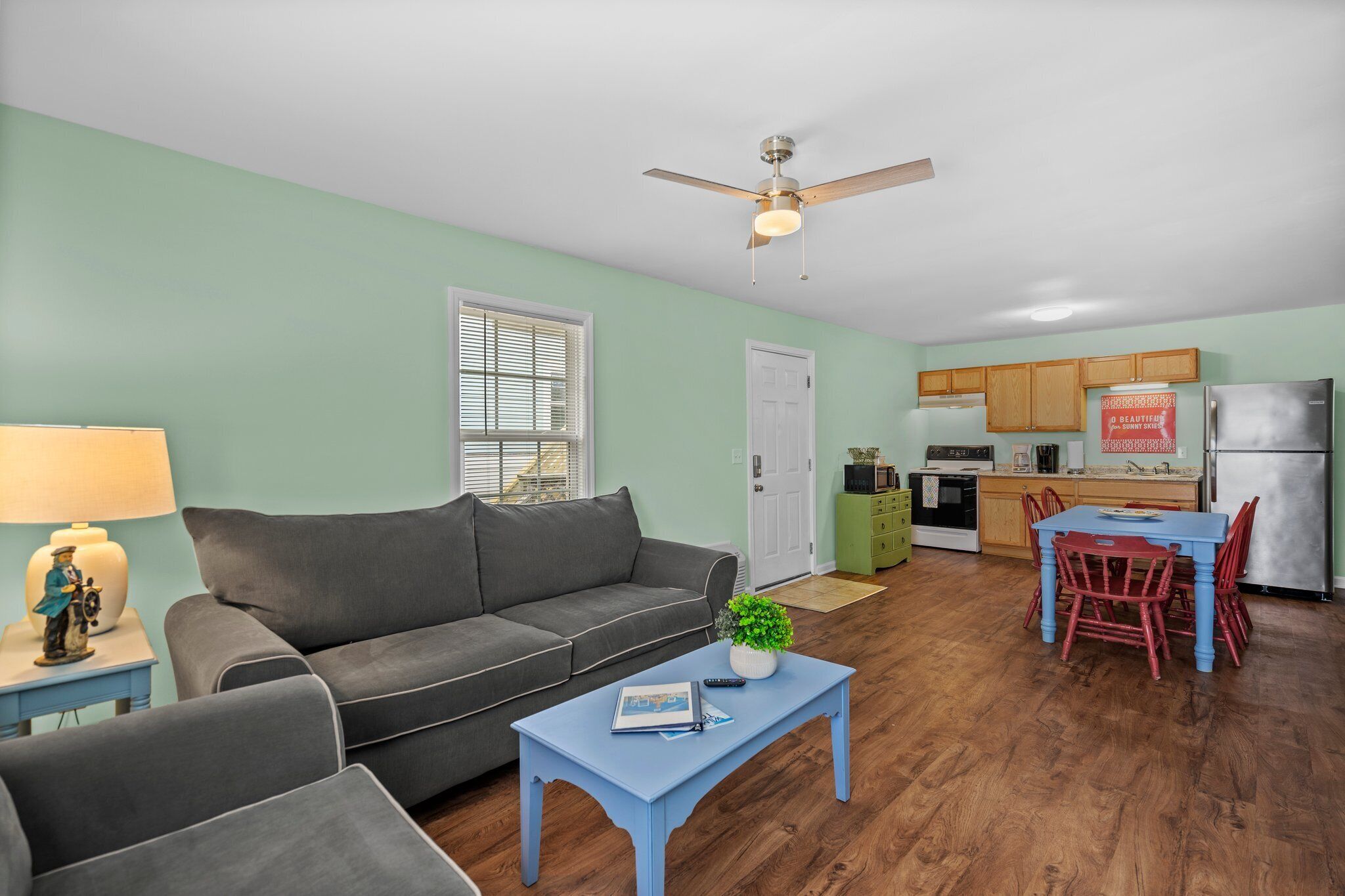 A living room with a couch, coffee table, and a dining area with chairs and a table.