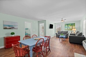 Relax in this open-plan living space with a dining area and seating area, featuring a dining table, sofa, and window.