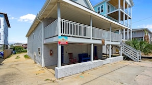 Un bâtiment à deux étages doté d’un balcon, d’une enseigne indiquant « Location de logements en bord de mer » et d’un escalier menant à l’étage supérieur.