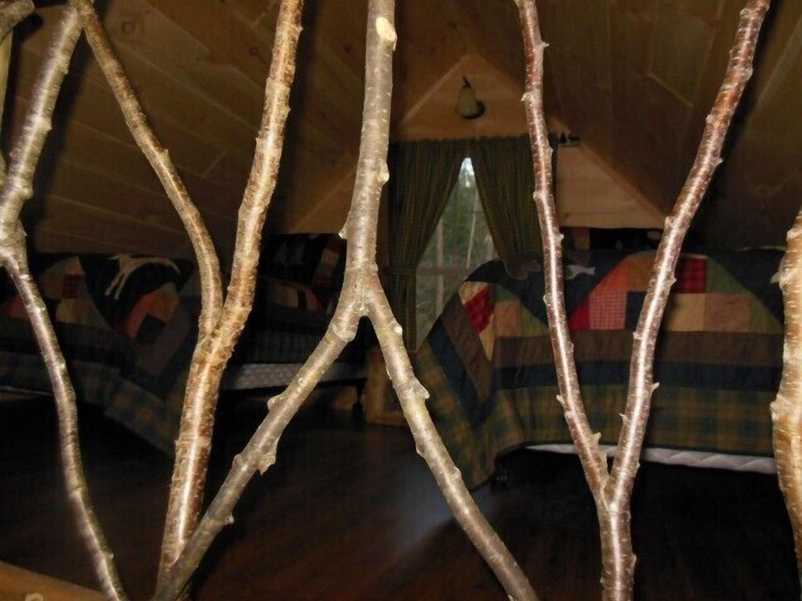 Una habitación acogedora con suelo de madera, una cama con colcha escocesa y una ventana con cortinas.