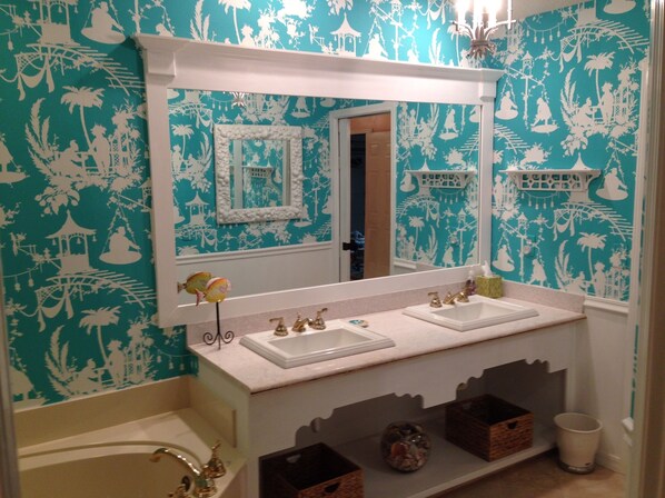 Un baño con dos lavamanos, un espejo grande y un detalle decorativo en la pared.