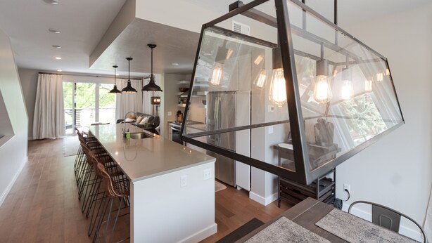 A modern kitchen with a large island, bar stools, pendant lighting, and a view of the outdoors. - 
Townhome with Stunning Views & Modern Finishes (Missoula)