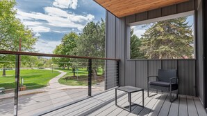 A balcony with a view of a park, a chair, and a table. - 
Townhome with Stunning Views & Modern Finishes (Missoula)
