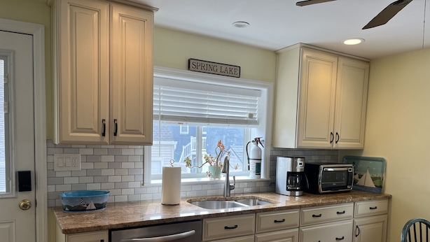 A kitchen with white cabinets, a stainless steel dishwasher, a sink, a coffee maker, and a microwave.