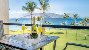 En balkong med ett bord dukat för två personer, med utsikt över en golfbana och havet.