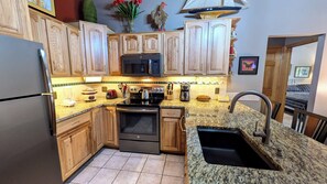 A kitchen with wooden cabinets, a stainless steel refrigerator, a microwave, a stove, and a sink. - Luxury Condo w/ FREE WiFi, Parking, Heated Pool, Hot Tubs, Skier Shuttles (Avon)