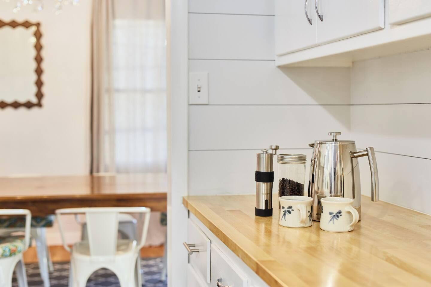 Una cocina con encimera de madera, una cafetera, un tarro y una taza.
